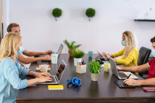 Group working around a table while using face masks.